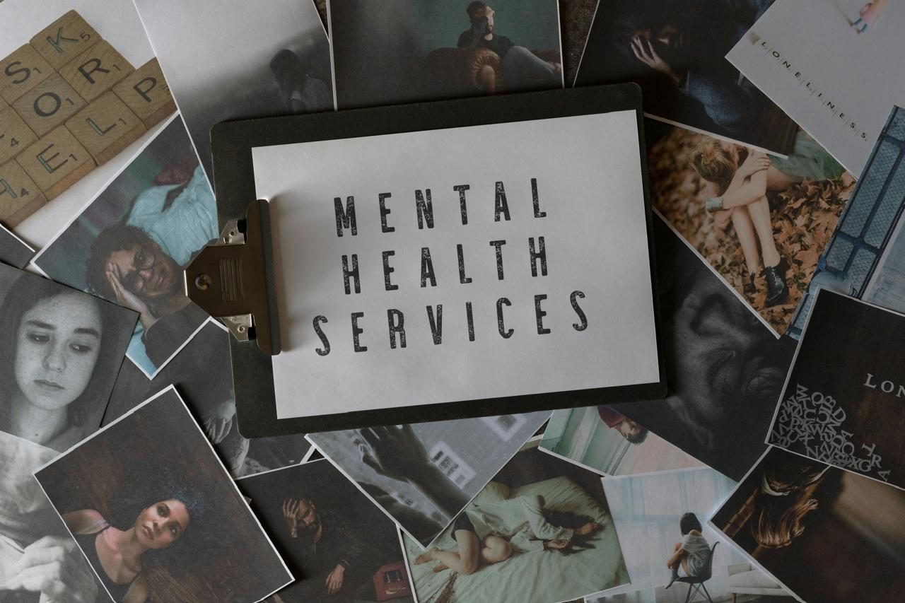A clipboard reading “Mental health services”, laid over scattered photographs