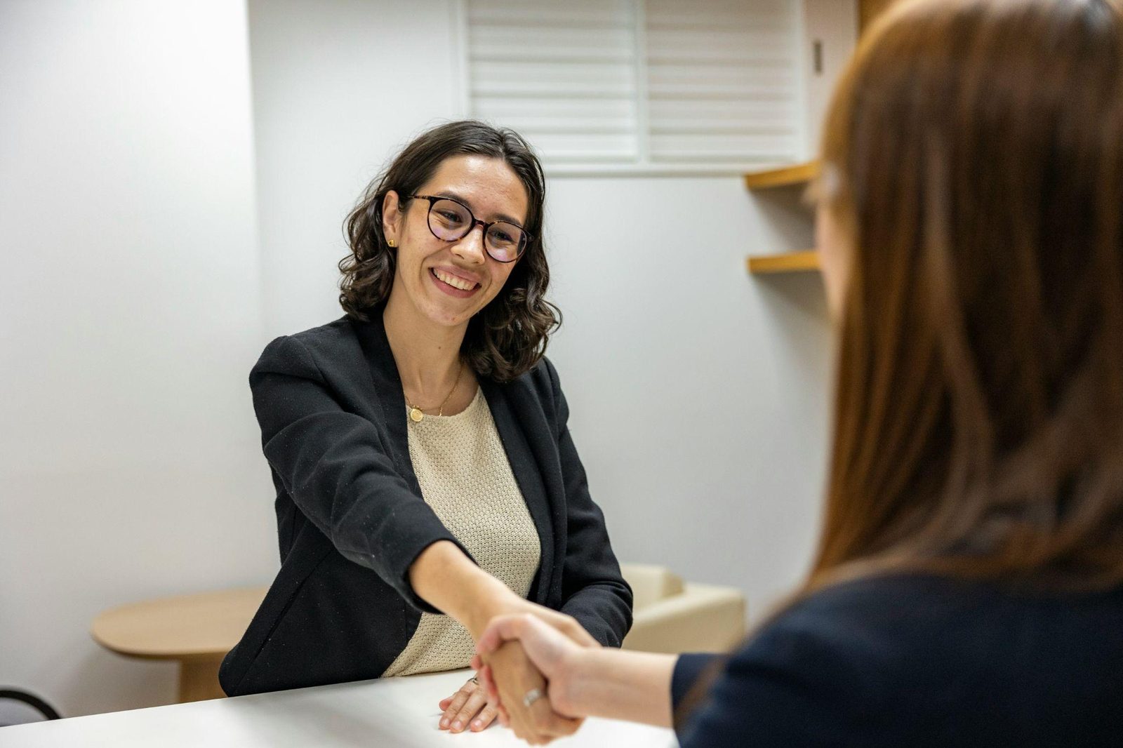 Two people shaking hands across a desk
