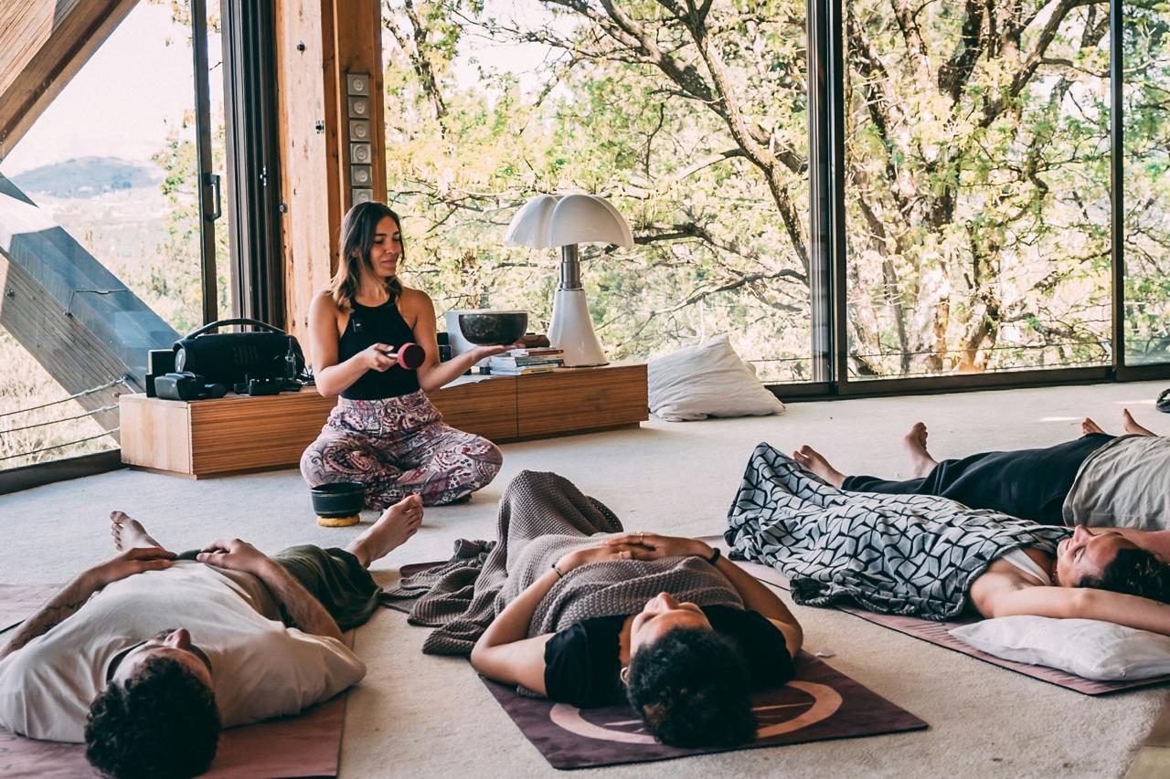 People lying on mats while a facilitator sounds a singing bowl