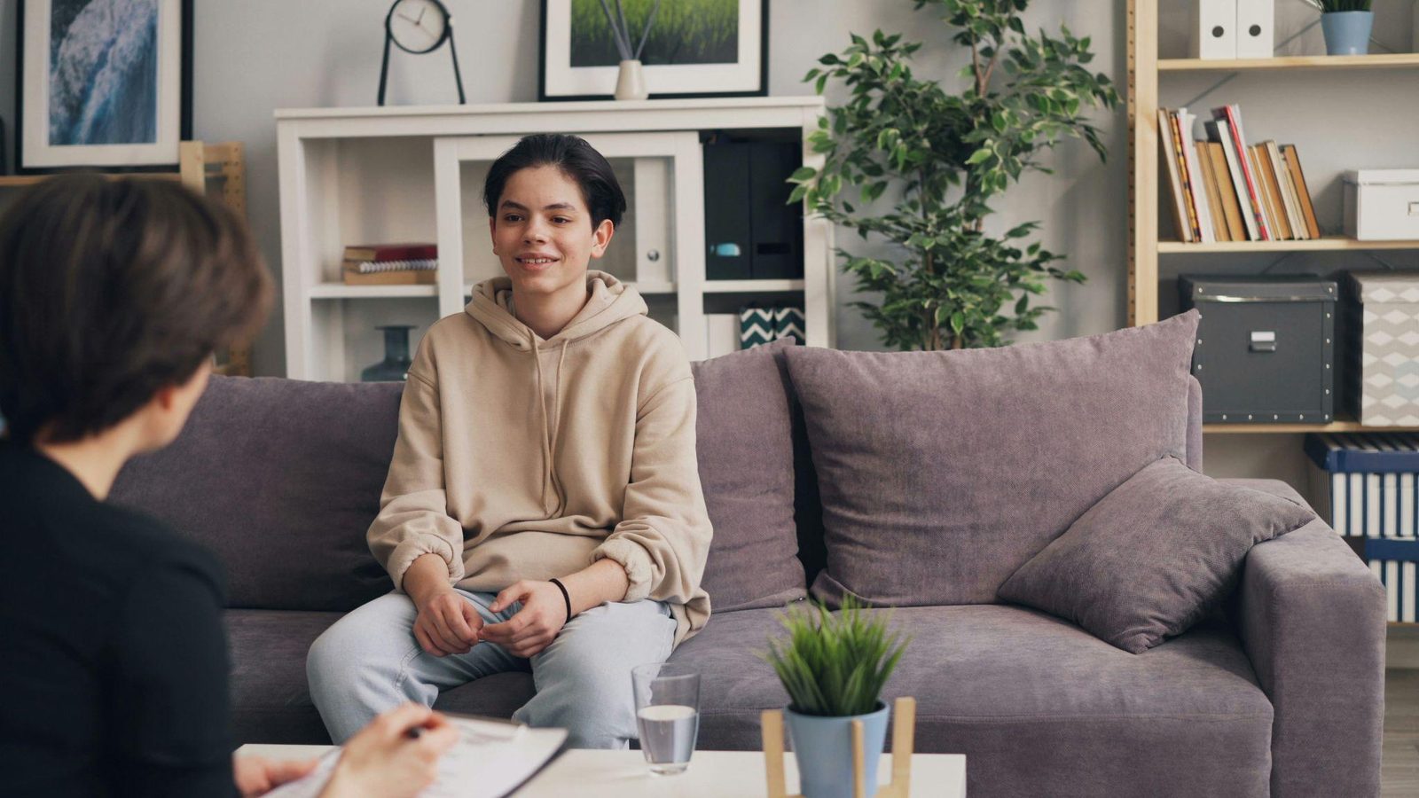 A teenager in conversation with a therapist in a bright room